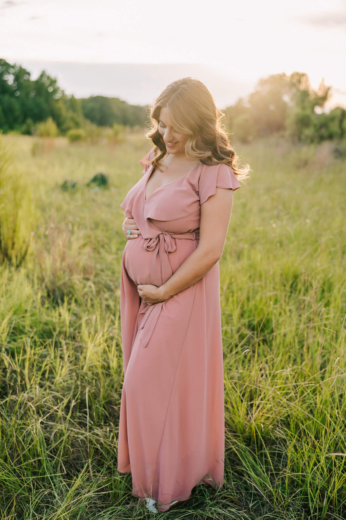 Mom wearing a blush gown smiling during her augusta ga maternity photography session