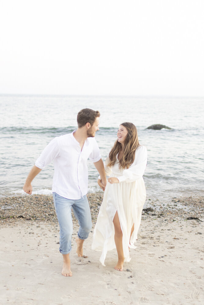 couple laughing on the beach together during engagement portraits