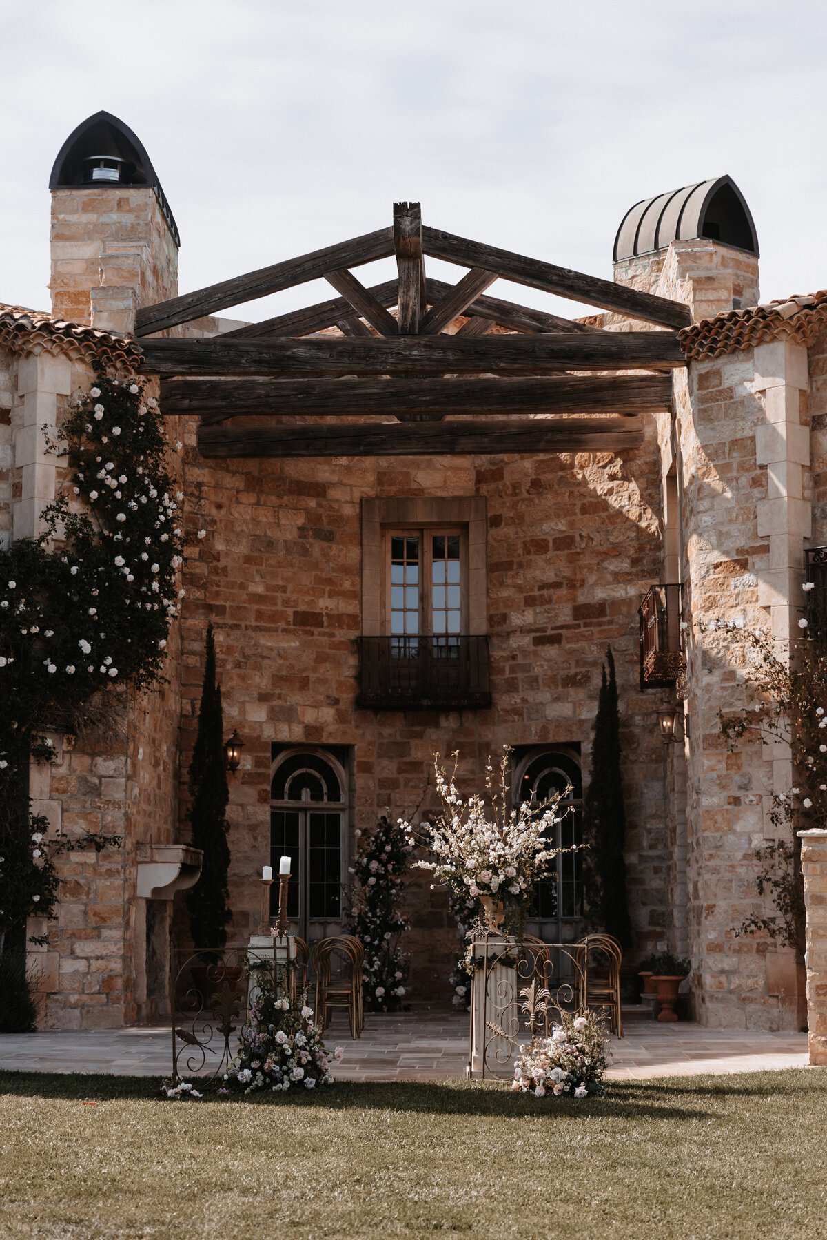 Rustic stone facade of Sunstone Winery adorned with floral arrangements for a wedding ceremony in Santa Ynez, California.