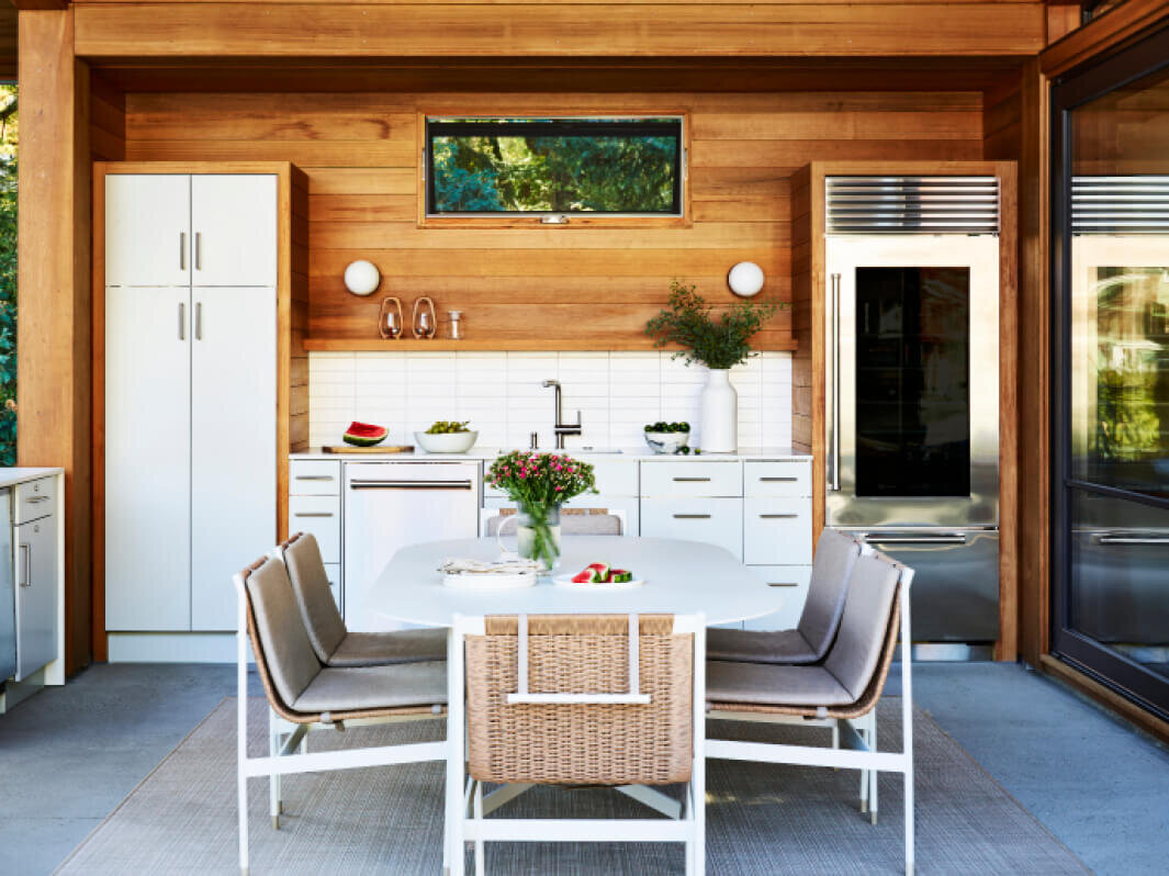 Outdoor kitchen design in Boston features light grey metal cabinets, red cedar siding, white counters, and a subway backsplash by a modern kitchen designer in Hingham.