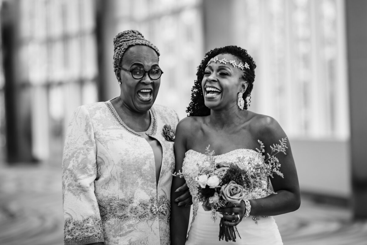 a black and white photo of a bride standing with her mom