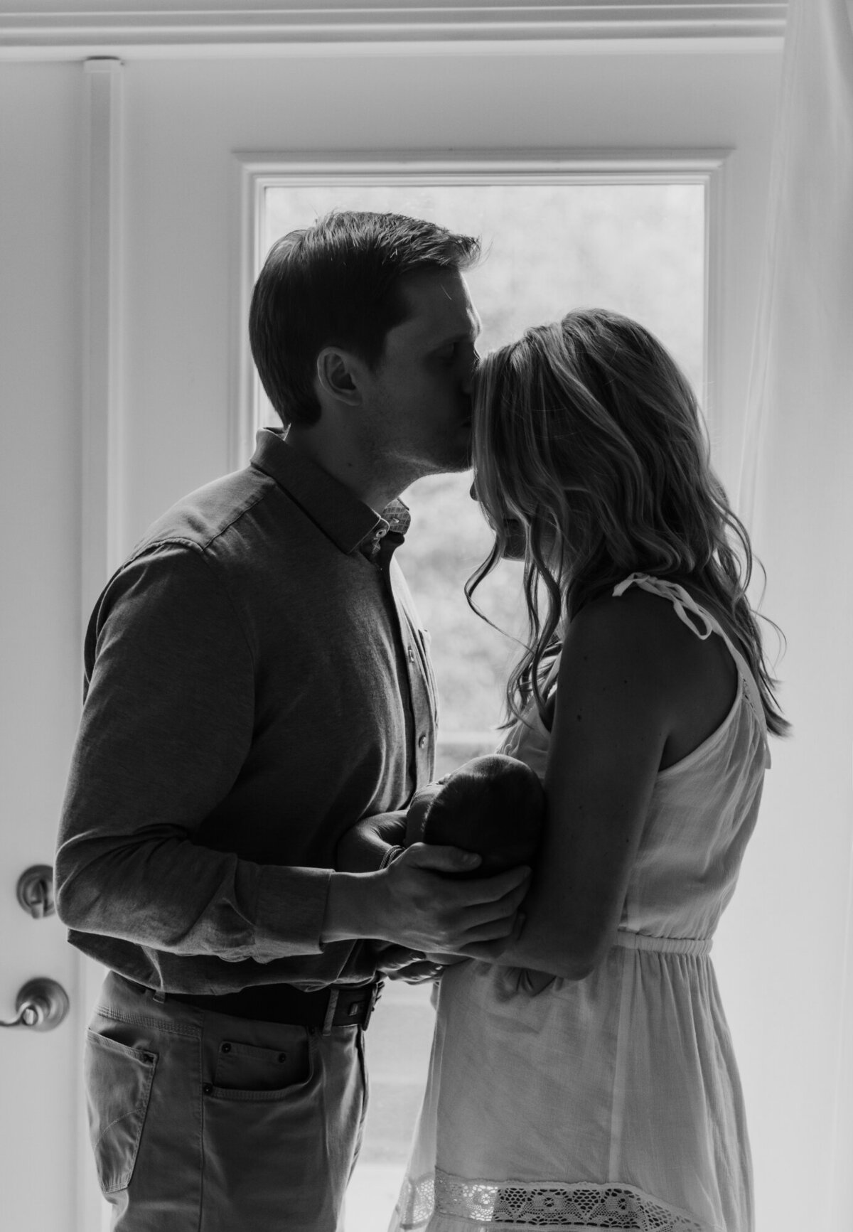 Newborn Photography, Silhouette of mom and dad kissing by the window.