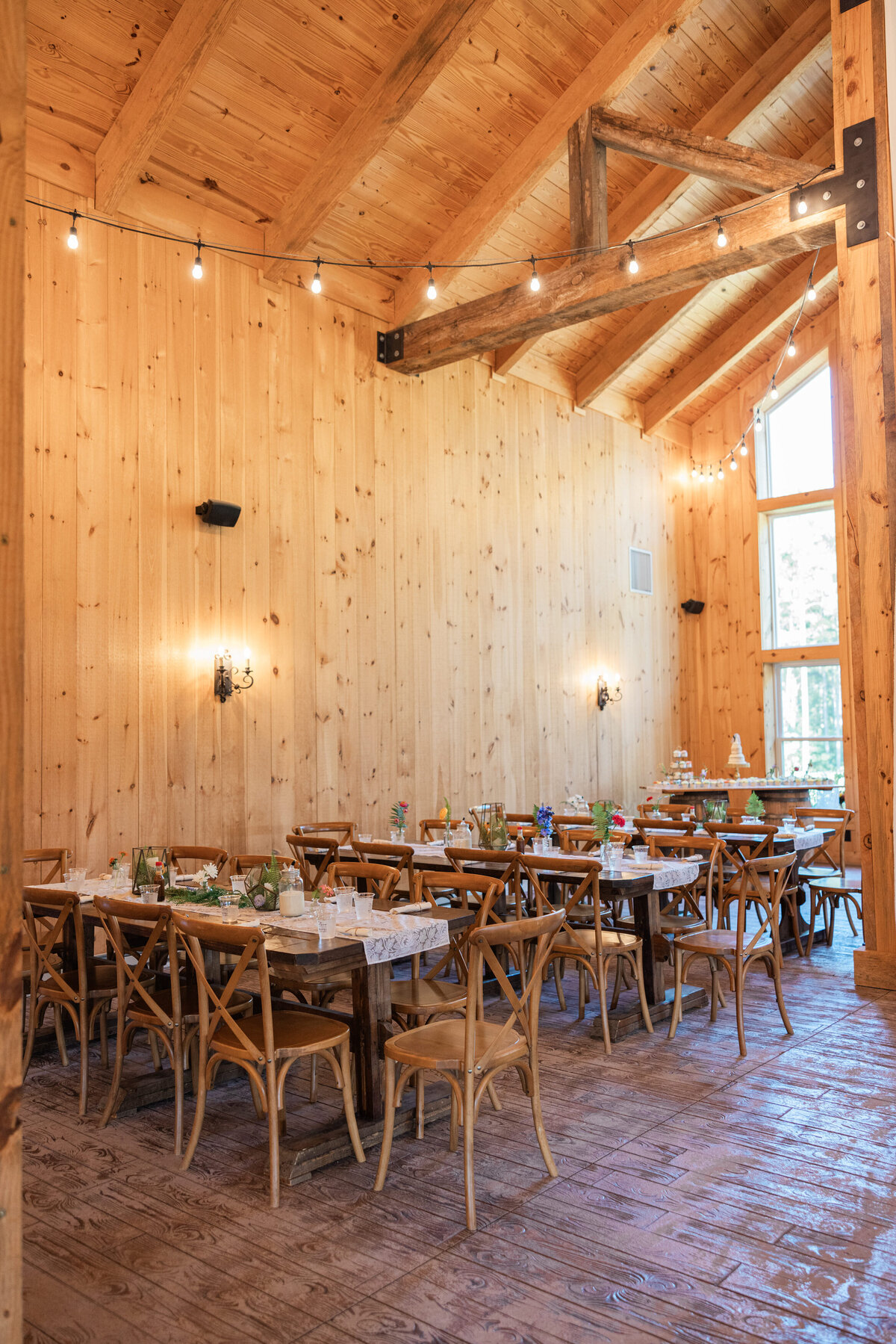 A barn-like reception hall with rectangular, wooden tables