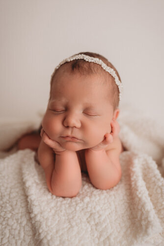 Baby girl sleeping for newborn portrait session with Atlanta Georgia newborn photographer snuggled up with chin resting on hands on neutral fabric backdrop