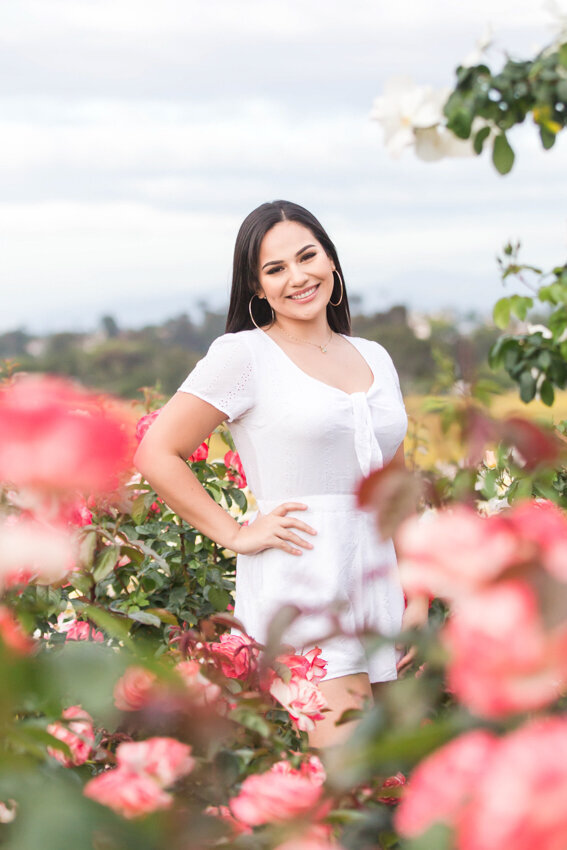 Senior girl standing in rose garden