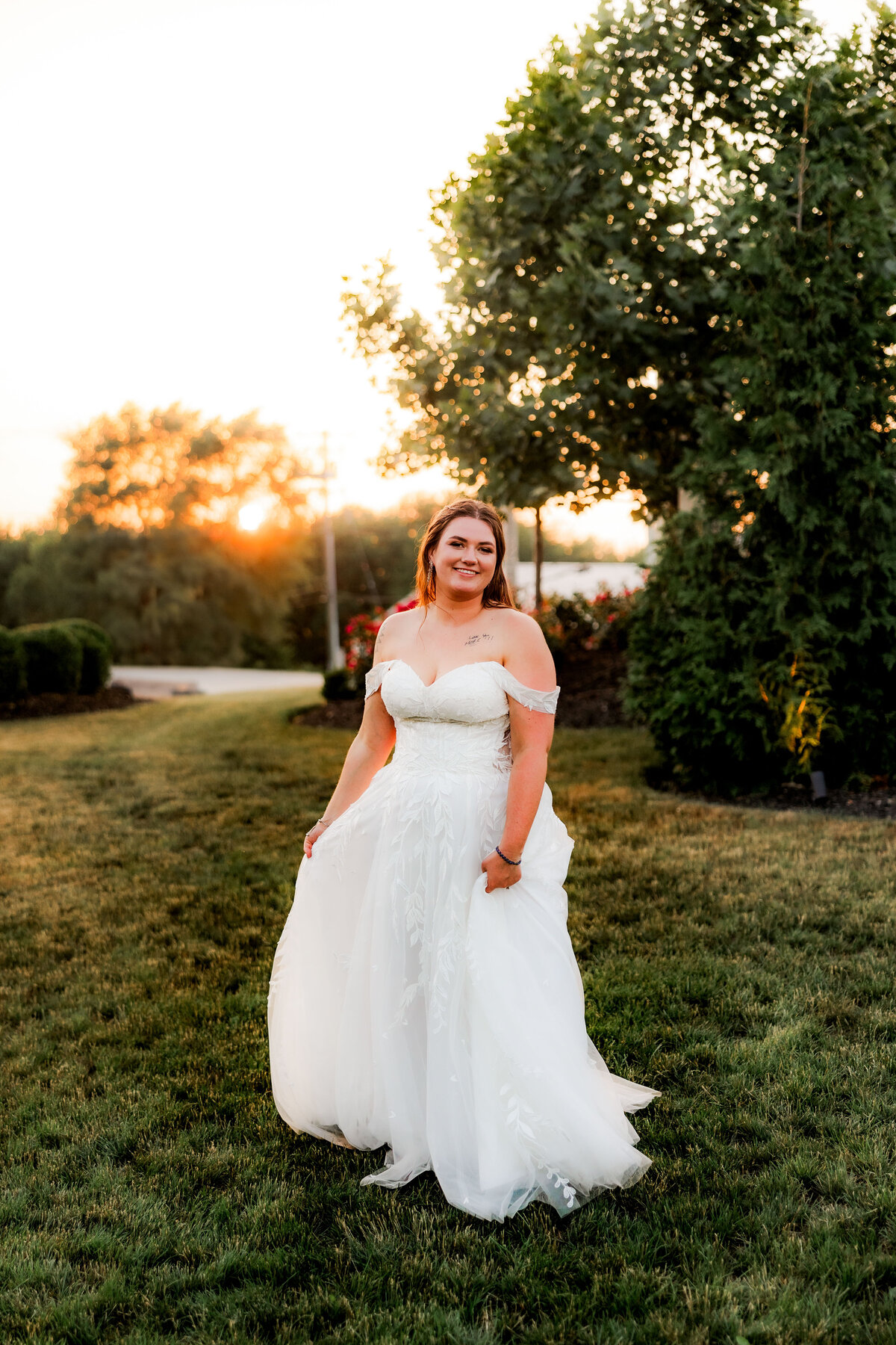 A bride swishes her dress in sunset.