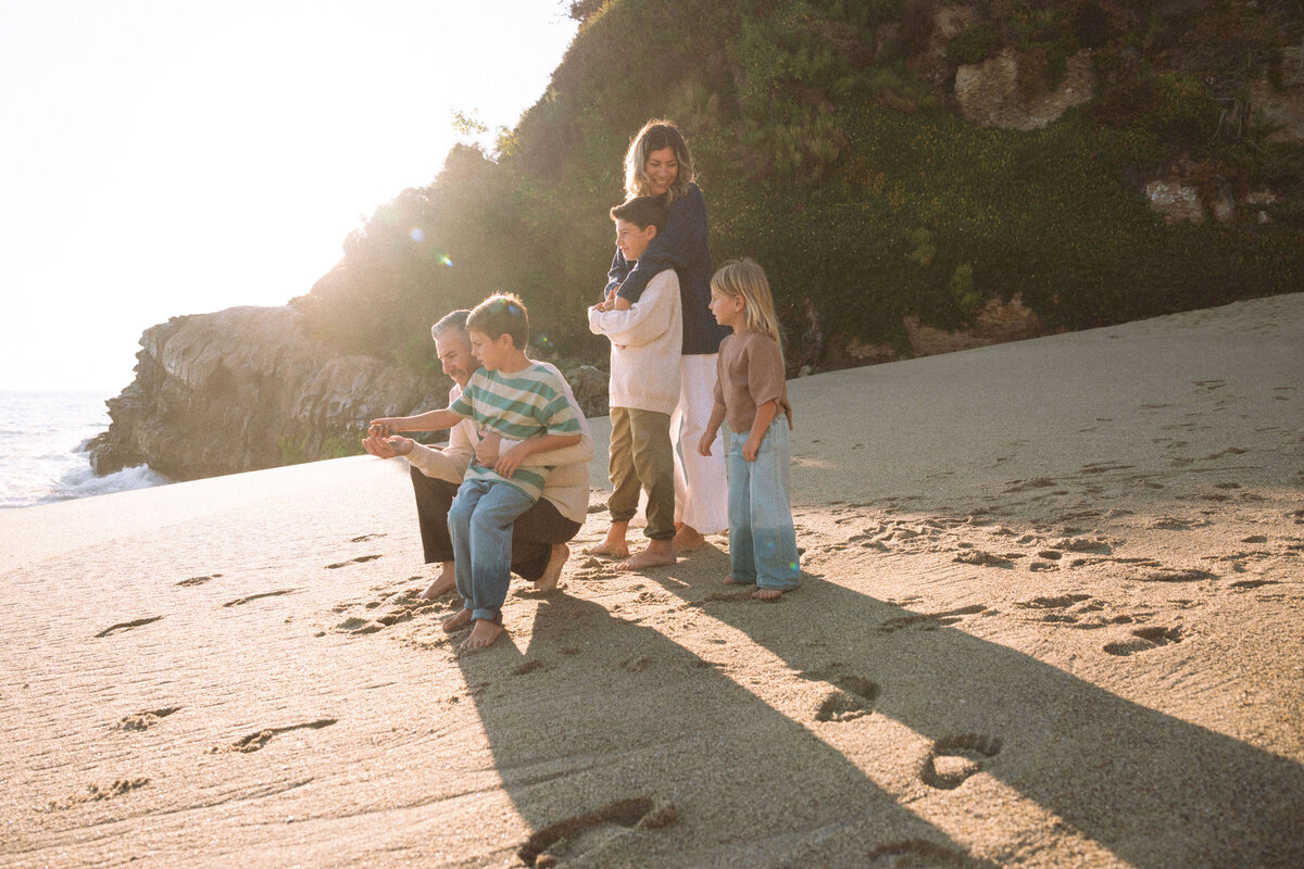 Laguna Beach family session with parents and kids enjoying golden light and relaxed beach moment captured in Orange County