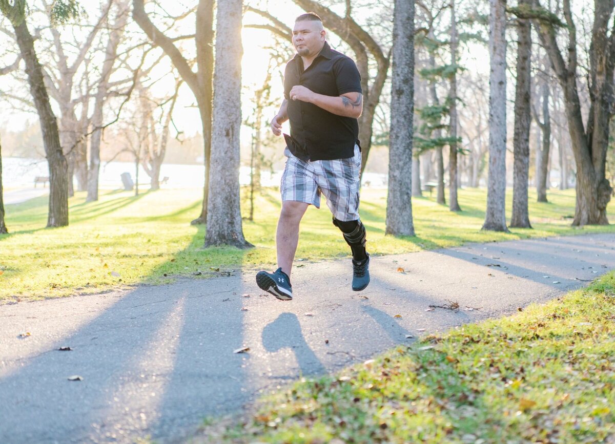 A man running in the park with a high-performance knee brace from Lethbridge Orthotics, known as the premier and industry-leading facility in Southern Alberta, Canada.