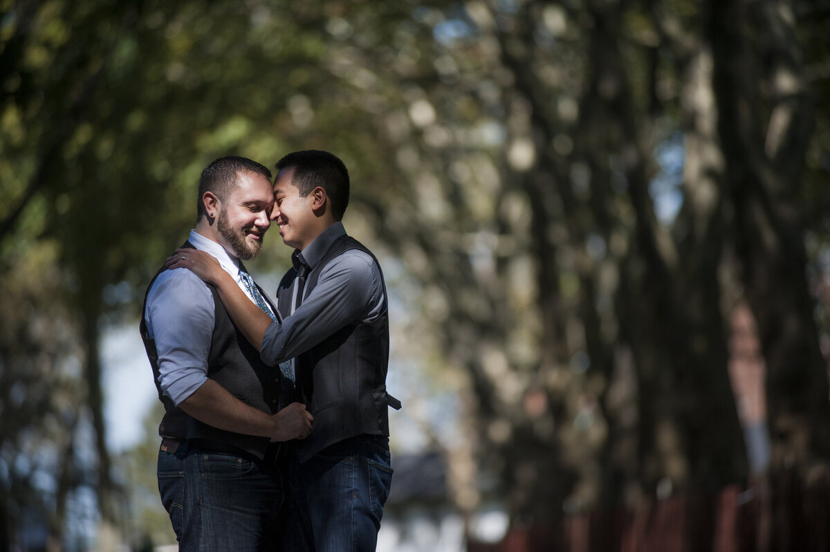 A couple with their arms around each other standing close in a park 
