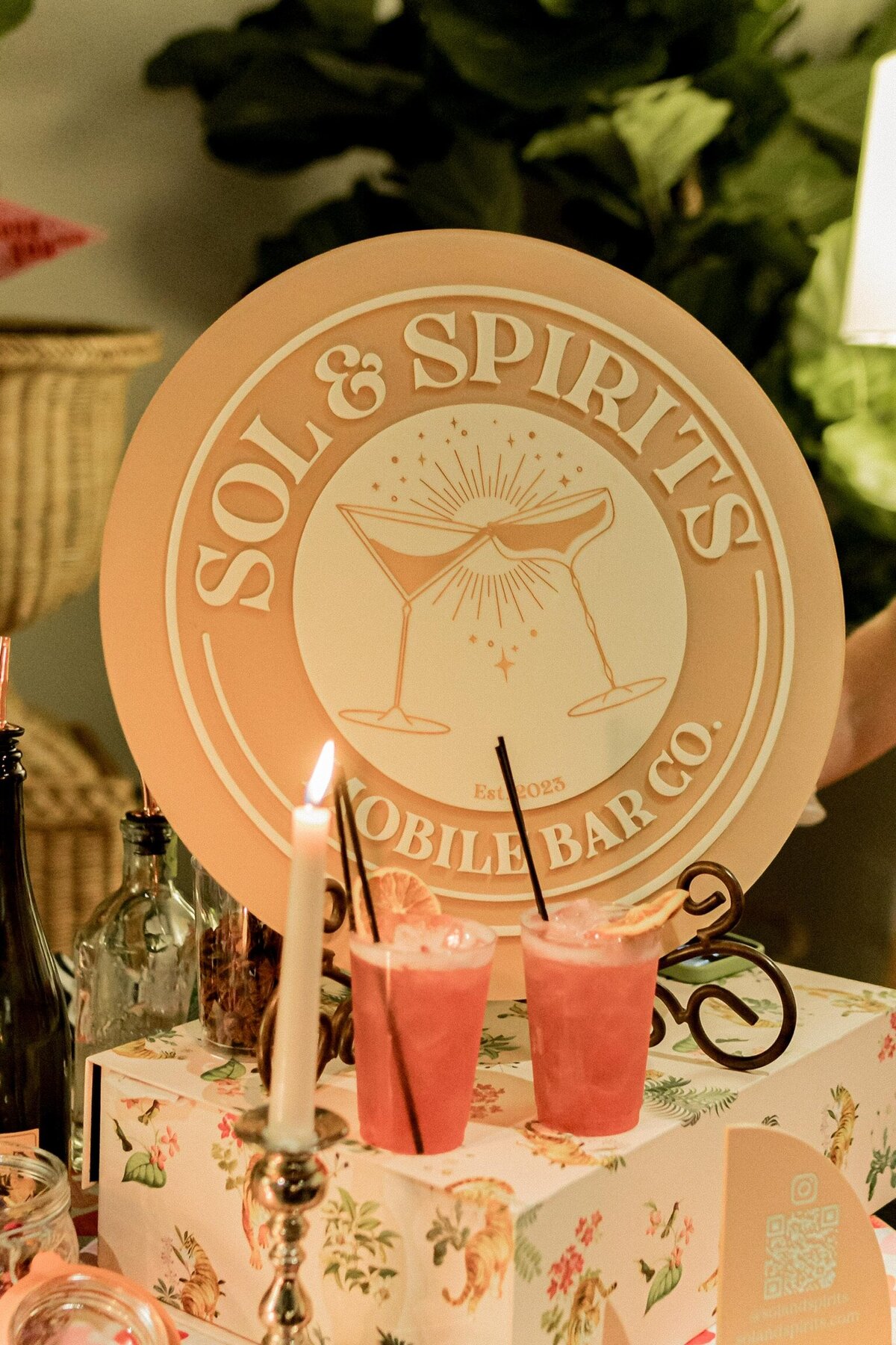 Sol & Spirits Mobile Bar Co. logo on sign on bar top next to drinks and candle