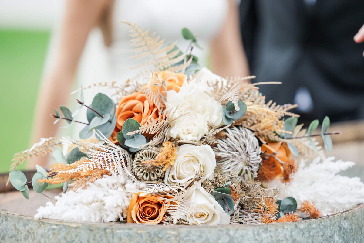 Bridal bouquet with orange, green and cream florals.