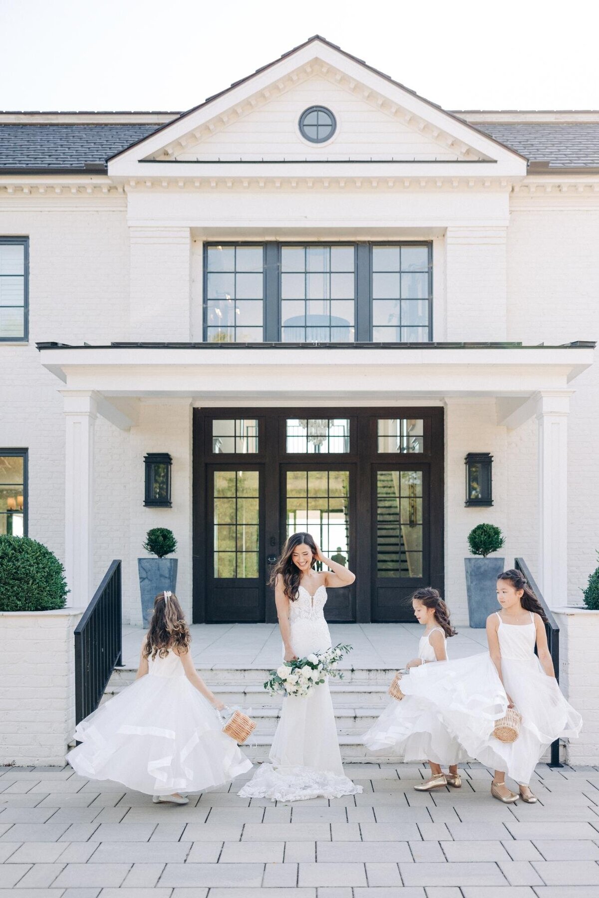 A bride standing at the entrance of a building with three young bridesmaids.