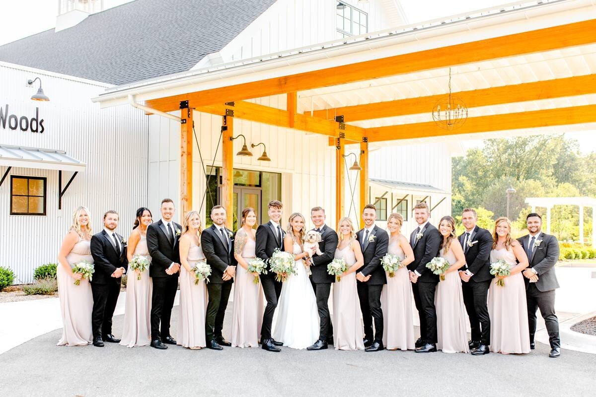 large bridal party with classic black and white suites and blush bridesmaid dresses