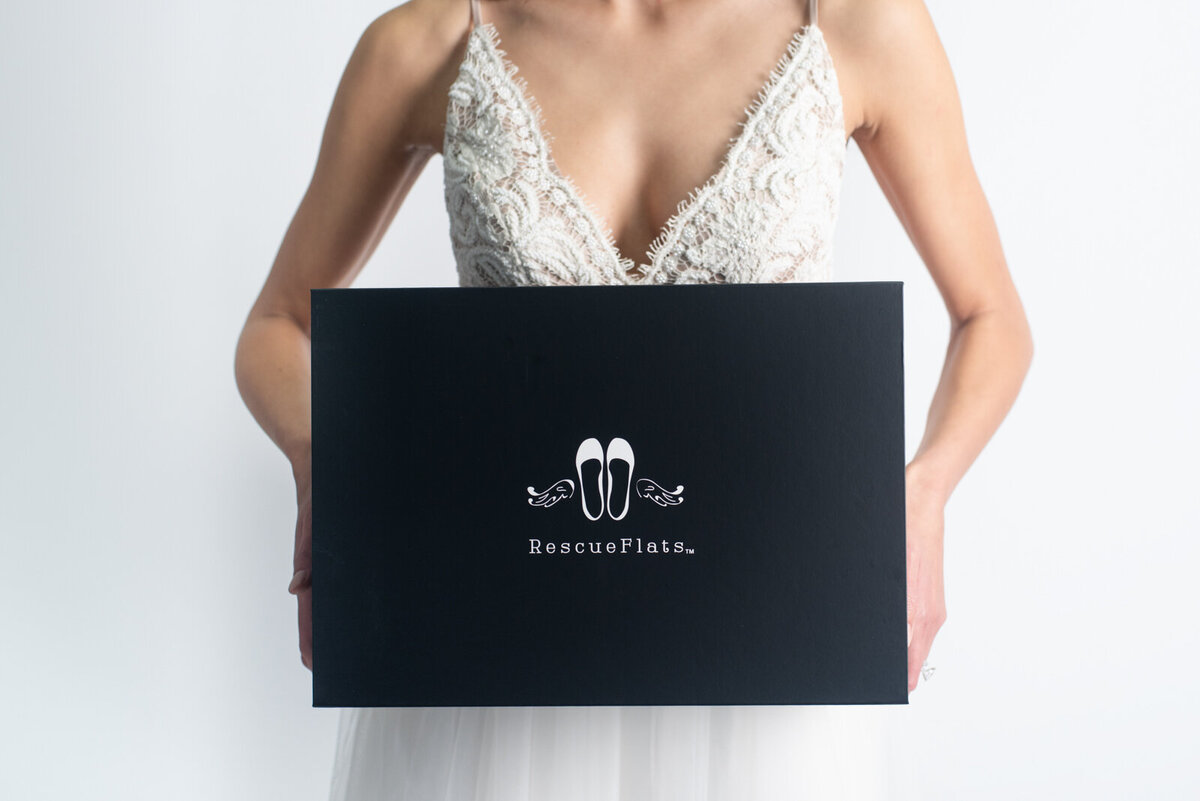 Bride holding a box of Rescue Flats, adorable foldable ballet flats based in Edmonton. Featured on the Brontë Bride Vendor Guide.