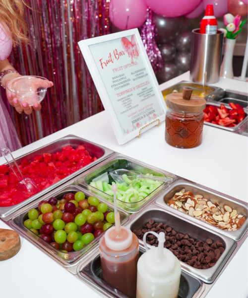 Fruit party cart with toppings and pink backdrop