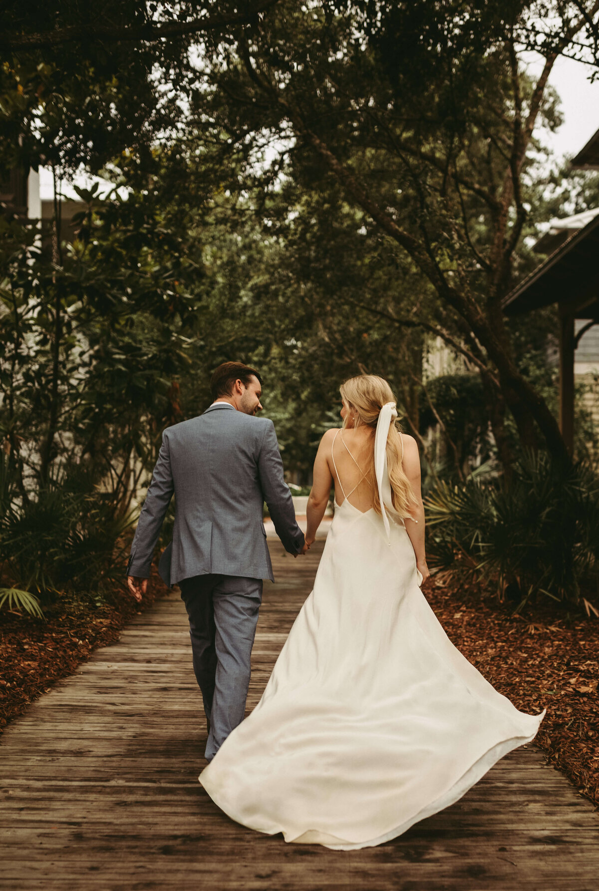 newlyweds hold hands and run with wedding dress flowing behind after private elopement in rosemary beach
