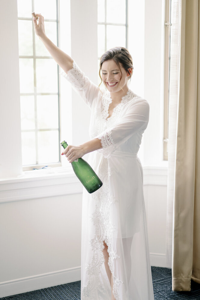 a bride opening a bottle of champagne