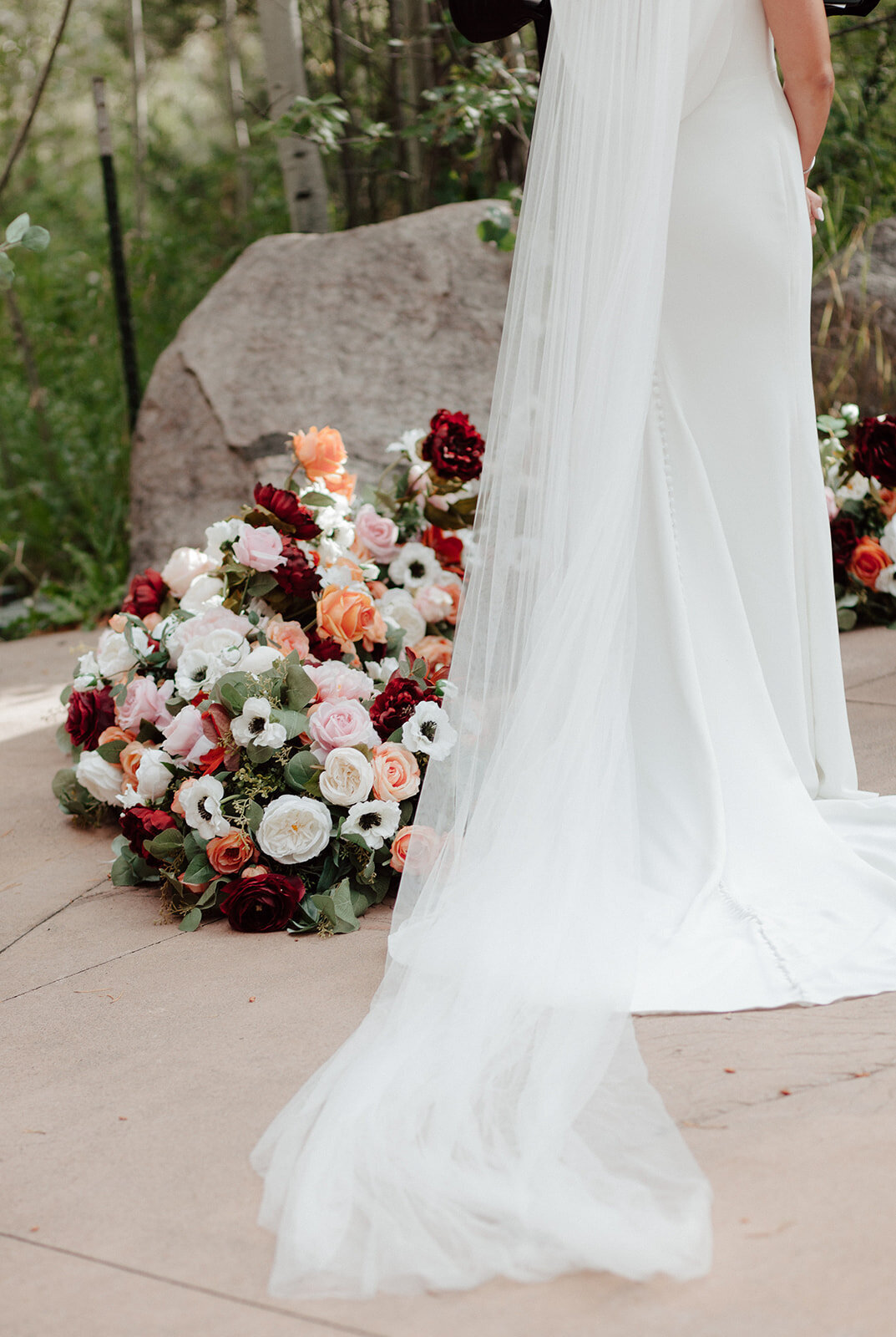 Bride wearing an elegant wedding gown and colorful florals beside her