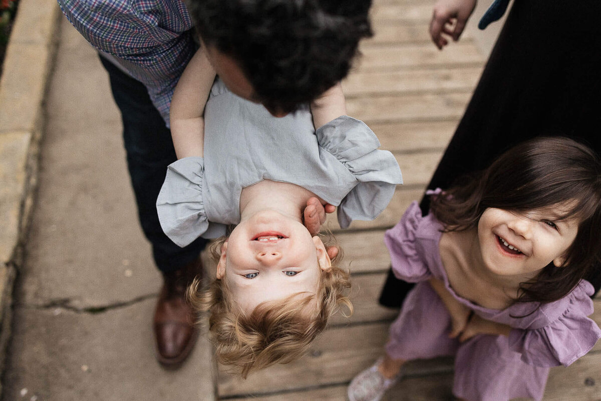 A joyful moment between father and daughters during family photography session at Rockefeller Greenhouse in Cleveland.