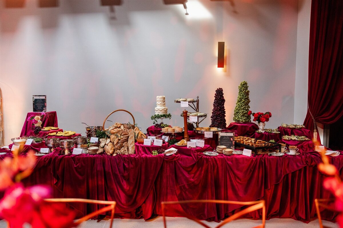 Venue space styled as a bread and butter station, featuring a rustic display of assorted artisan breads, flavored butters, and decorative serving boards arranged on a linen-covered table