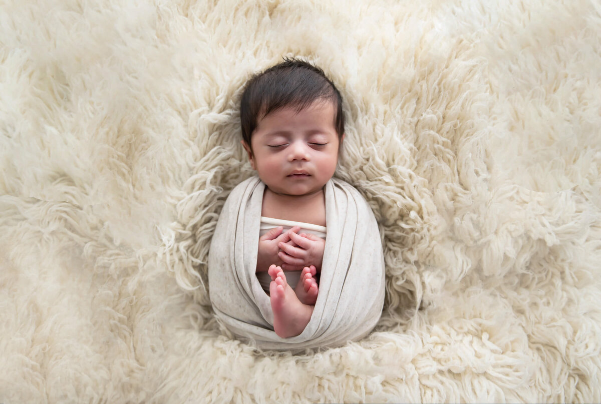newborn boy wrapped in beige on a cream rug for his Burlington, ON newborn photos