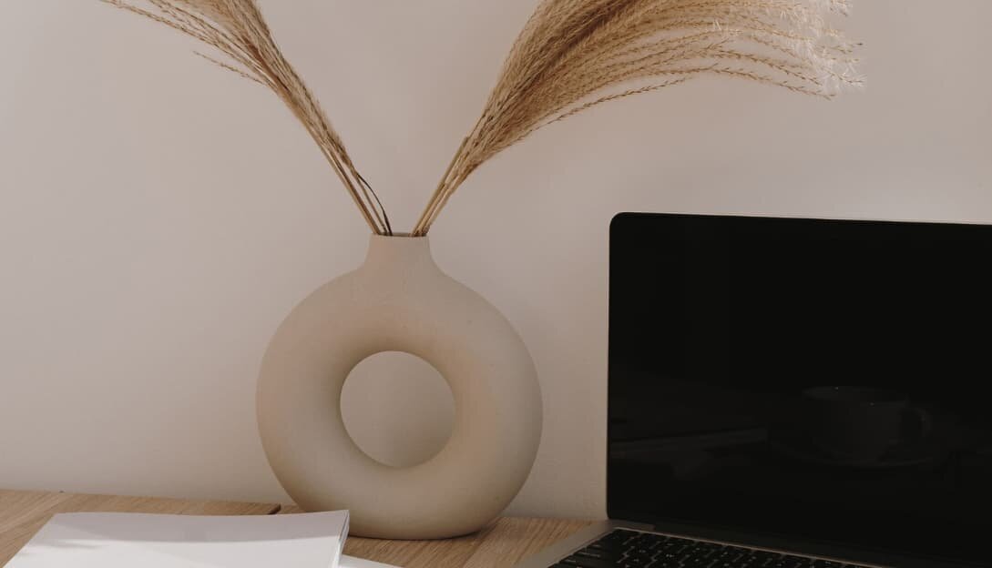 Laptop on a table with notebook and coffee, representing website design services for creative entrepreneurs.
