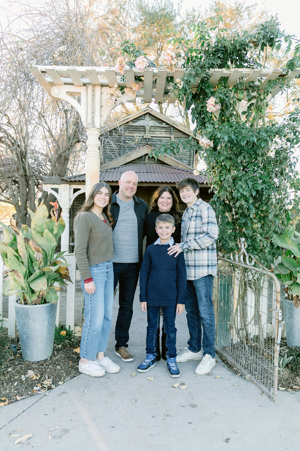 Family of five stand under an arch outdoors