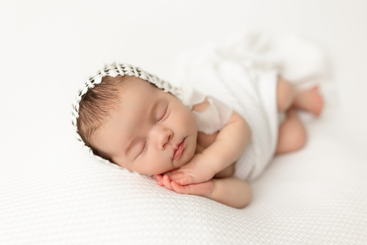 Newborn baby girl posed on white backdrop