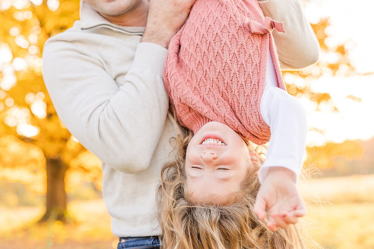 dad holds girl upside down  during outdoor newborn photo session with Sara Sniderman Photography in Natick Massachusetts
