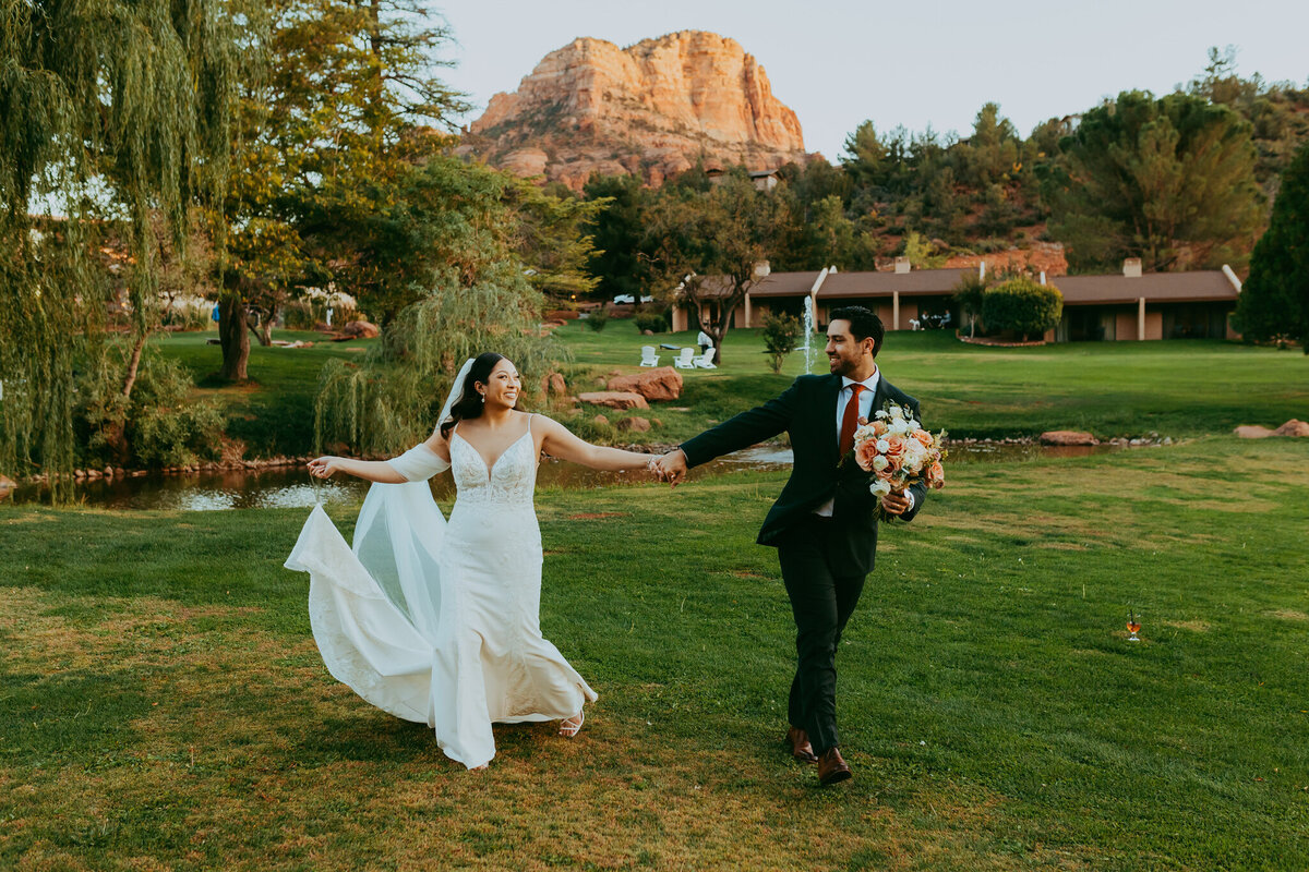 wedding couple walking with poco diablo resort in background in sedona