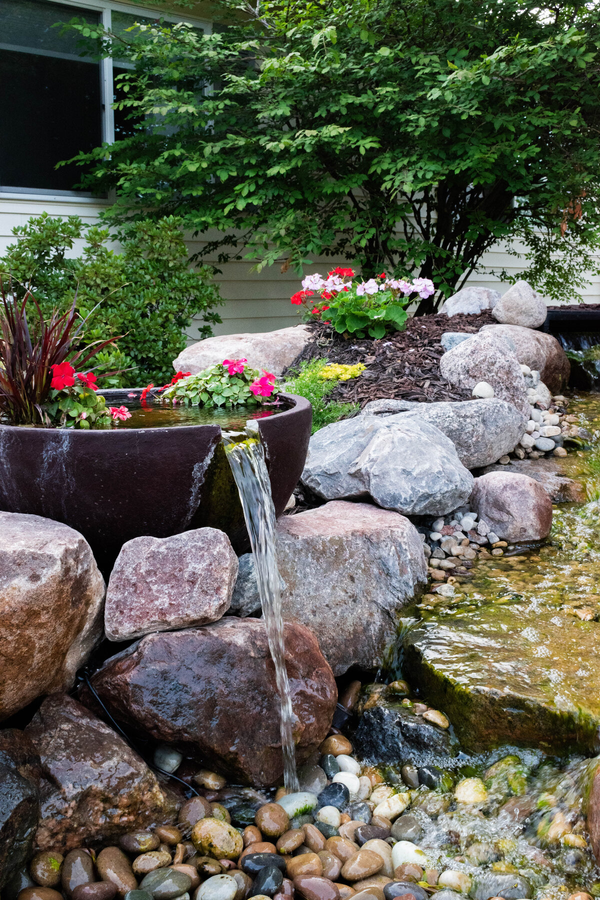 Spillway bowls with potted pond plants spilling water into waterfall feature