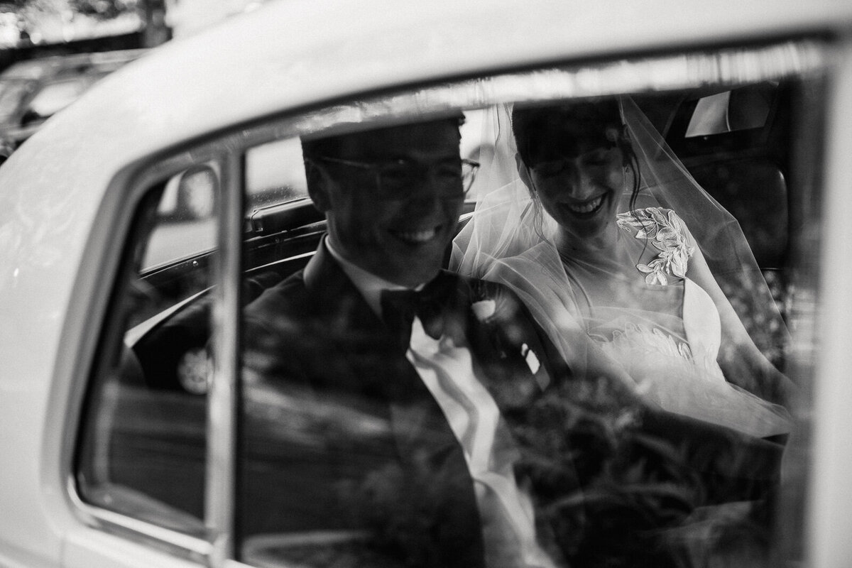 Black and white wedding photo of couple kissing in a old school car