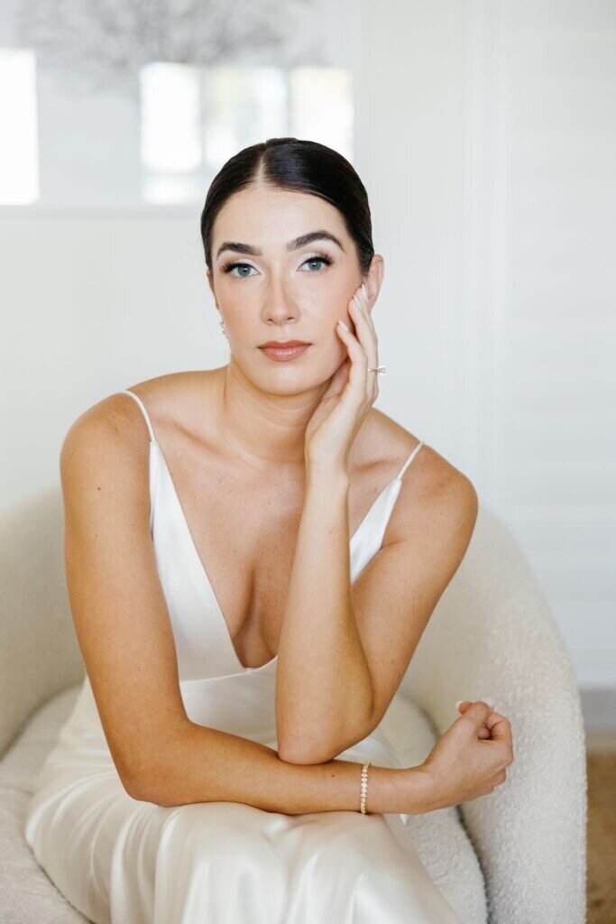A sophisticated bridal portrait featuring the bride in a sleek satin wedding gown, seated with a timeless, poised expression. Destination wedding photography by Claudia Amalia Photography in the Florida Keys.