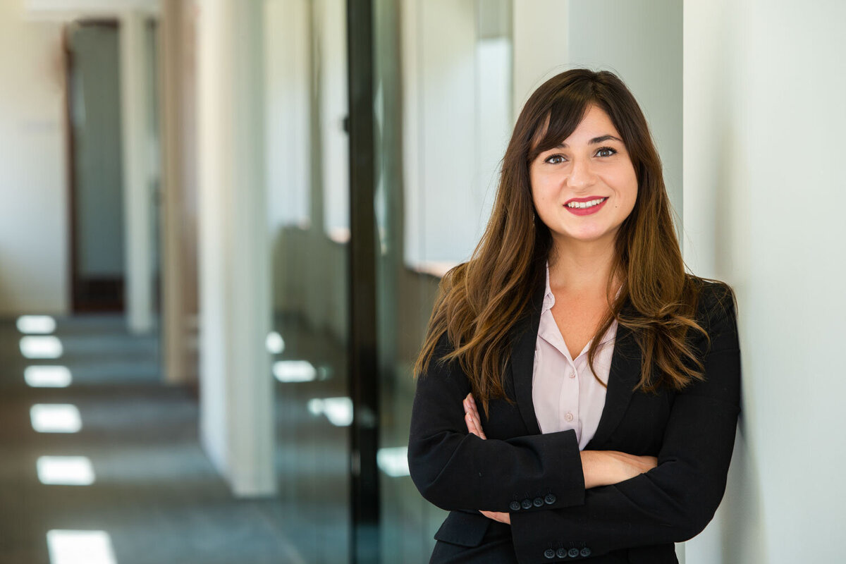 Woman in black suit smiling in office hallway