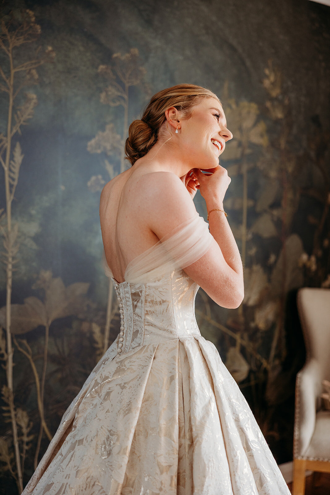 Bride puts in her earrings and smiling while getting ready for her wedding ceremony at Petrichor Farm