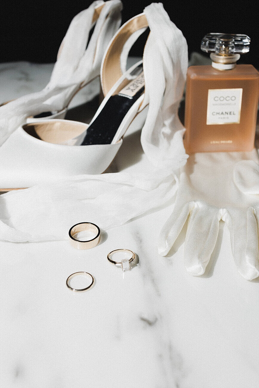 wedding rings, shoes, gloves, and perfume on table
