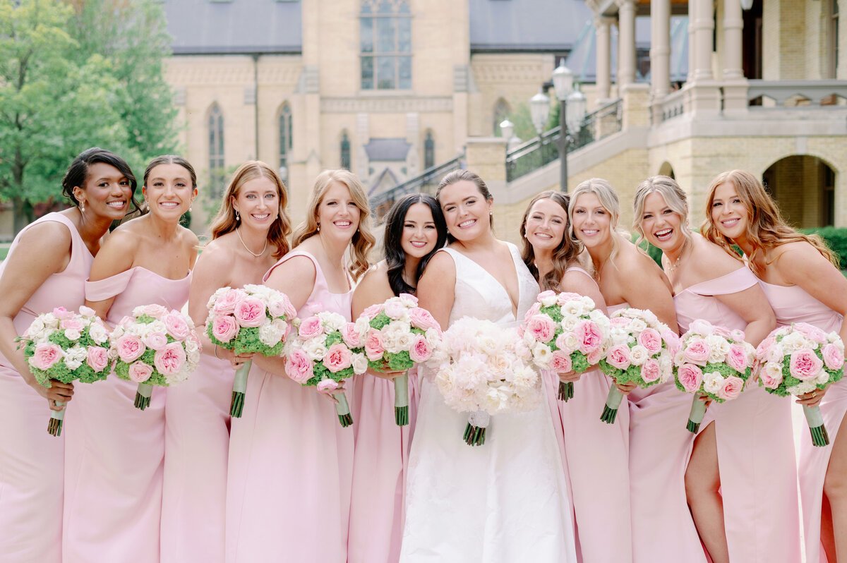 bridesmaids in pink dresses posing with a Notre Dame bride