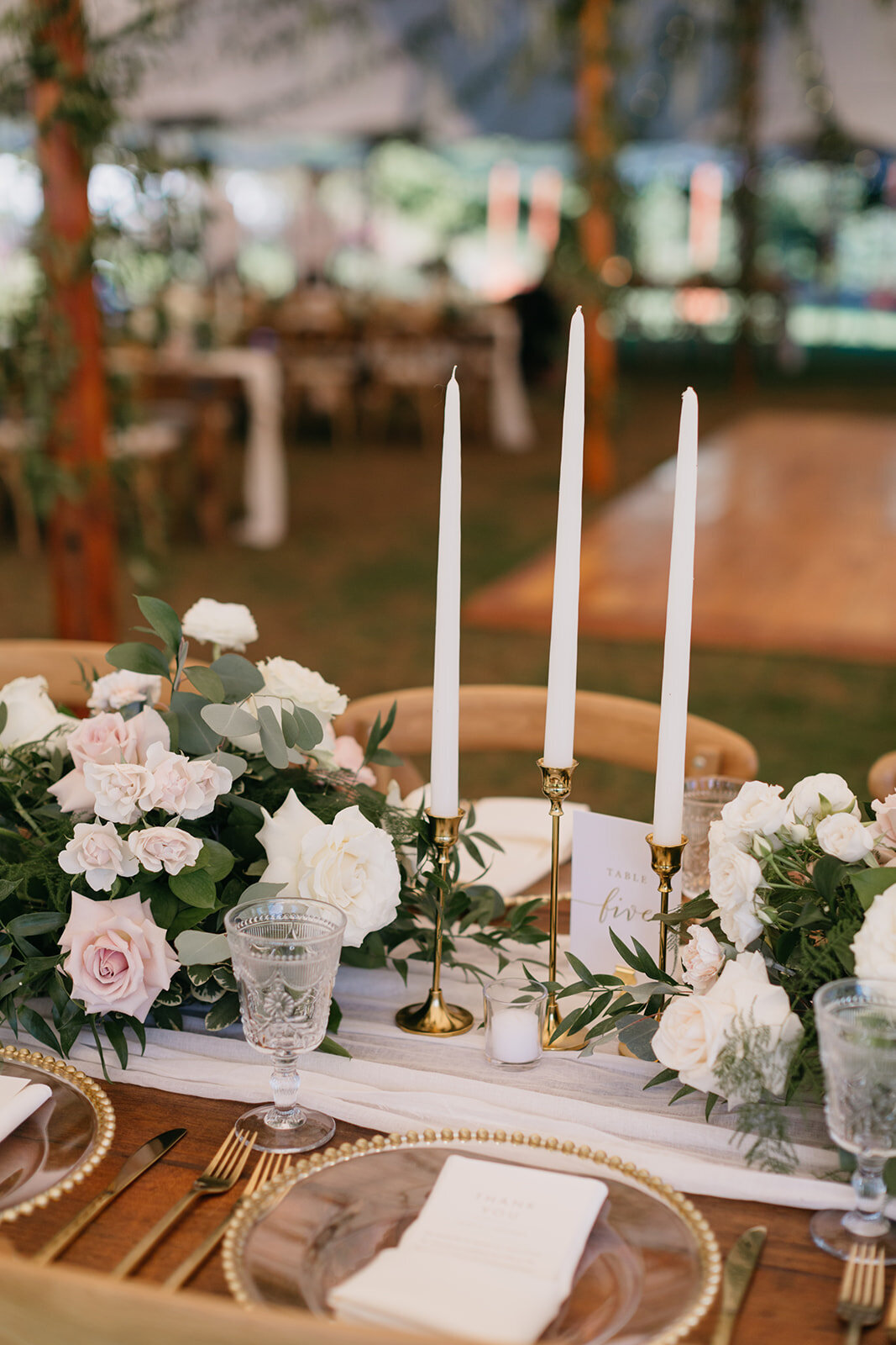 Farm table with lush centerpieces and taper candles with gold candlesticks