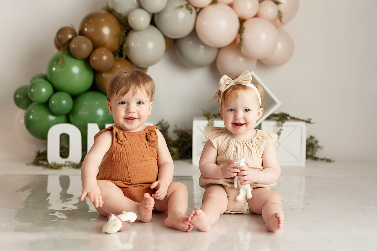 Twin babies smiling during their one year milestone session.