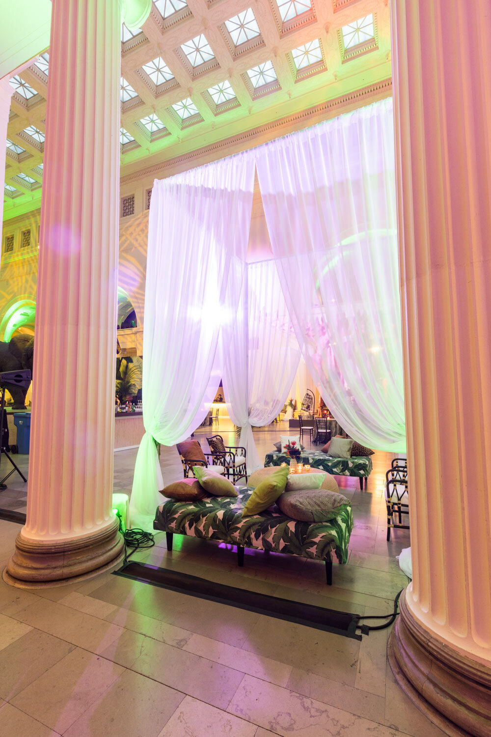 Elegant lounge under white drapery between grand columns.