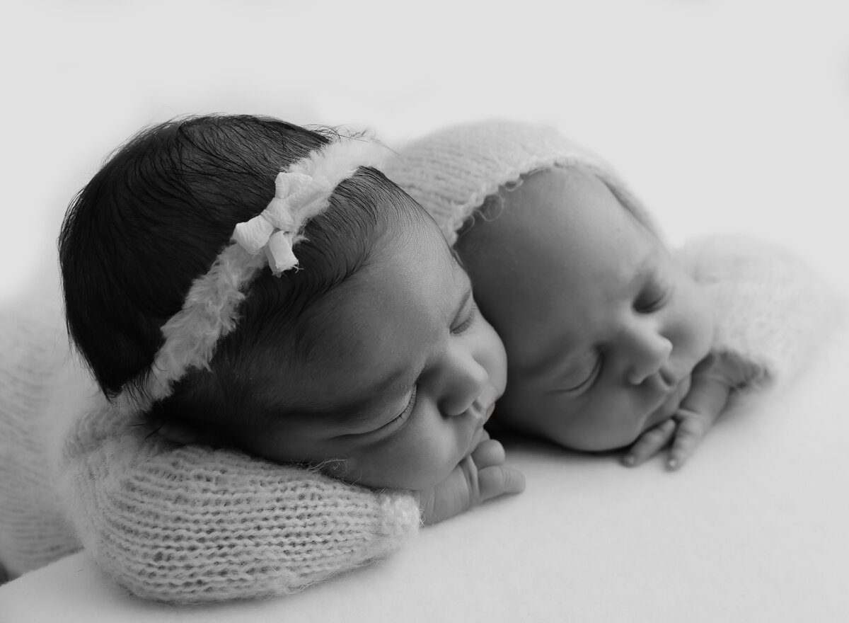Brooklyn Newborn twin photoshoot. Twins are sleeping on their belly with their hands folded under their chins. Their heads are resting together. Captured by top Brooklyn newborn photographer Chaya Bornstein