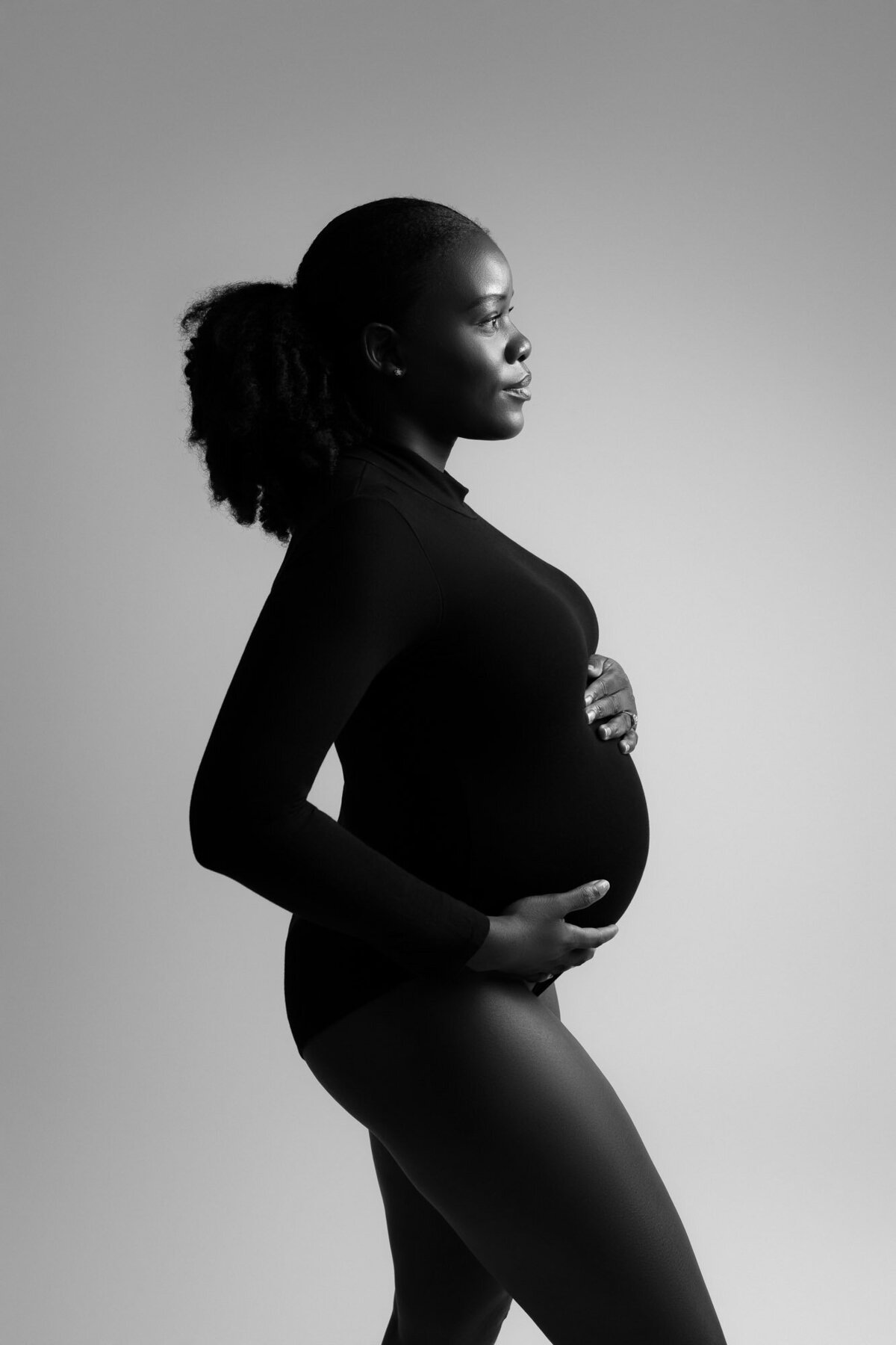 Artistic black and white maternity silhouette profile showcasing pregnant belly curves