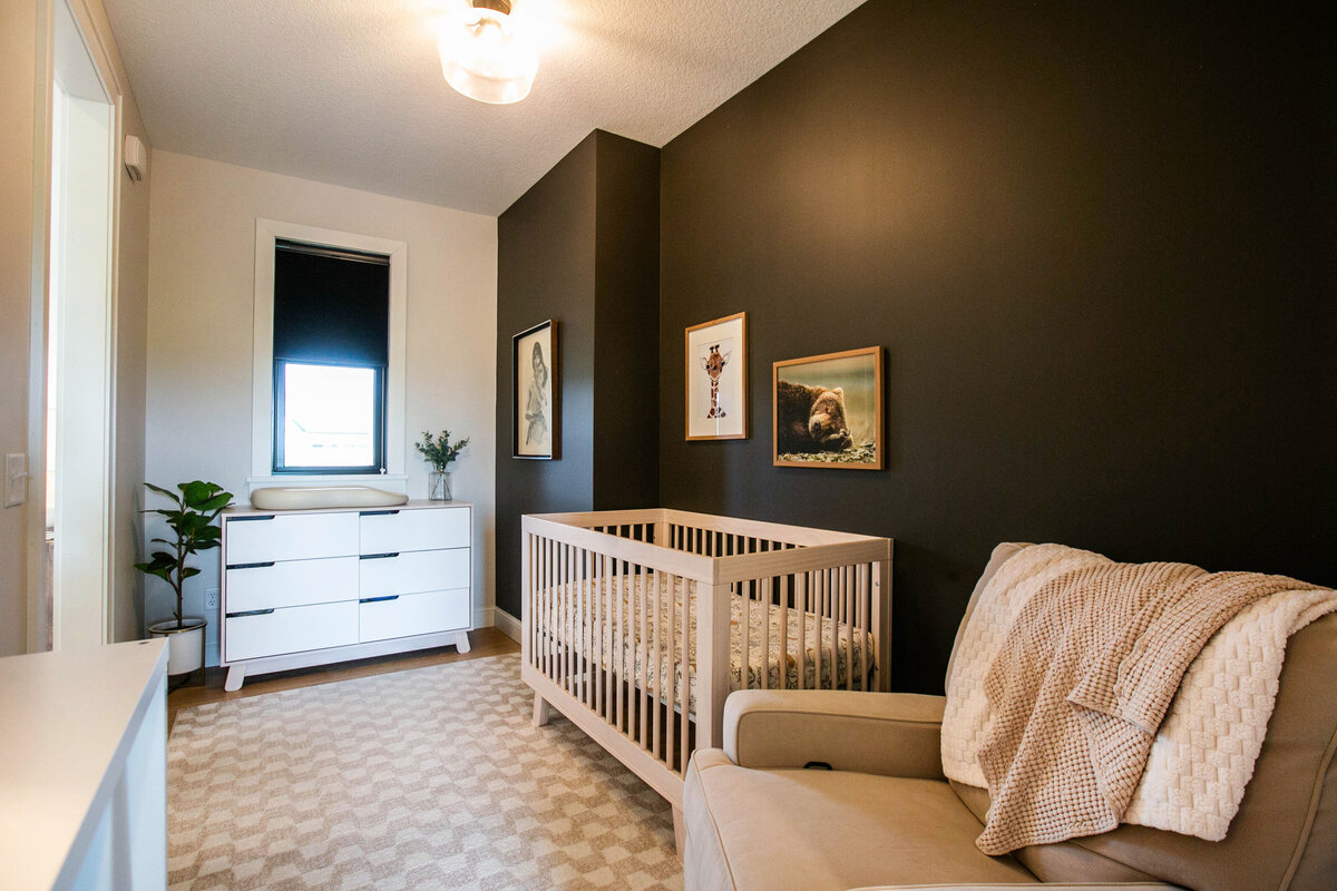 Custom nursery nook in Otsego home with dark walls, wood floors and modern accents designed by Cornerstone Custom Builds