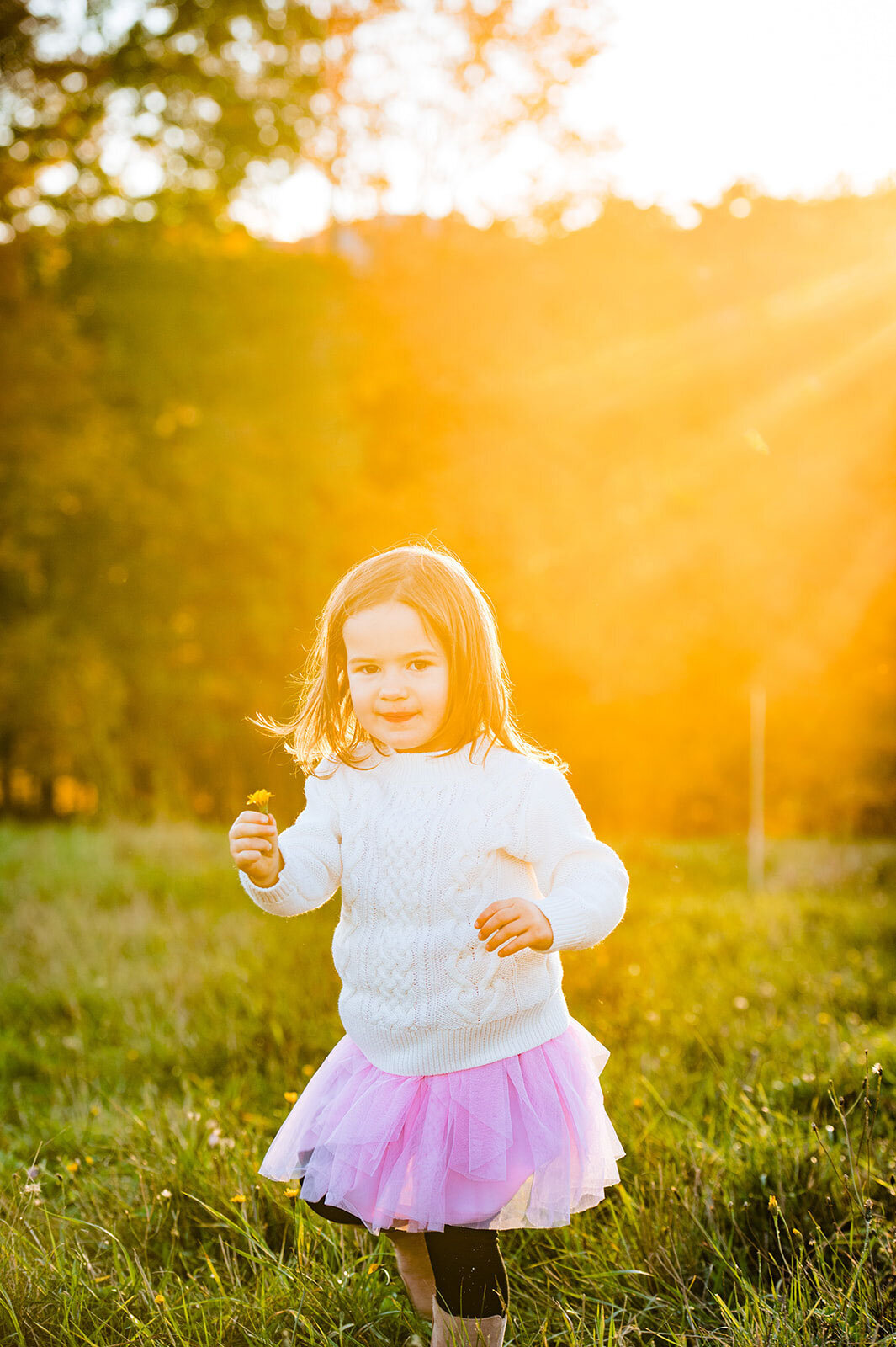toddler girl holding flower in sunset trapp family lodge stowe
