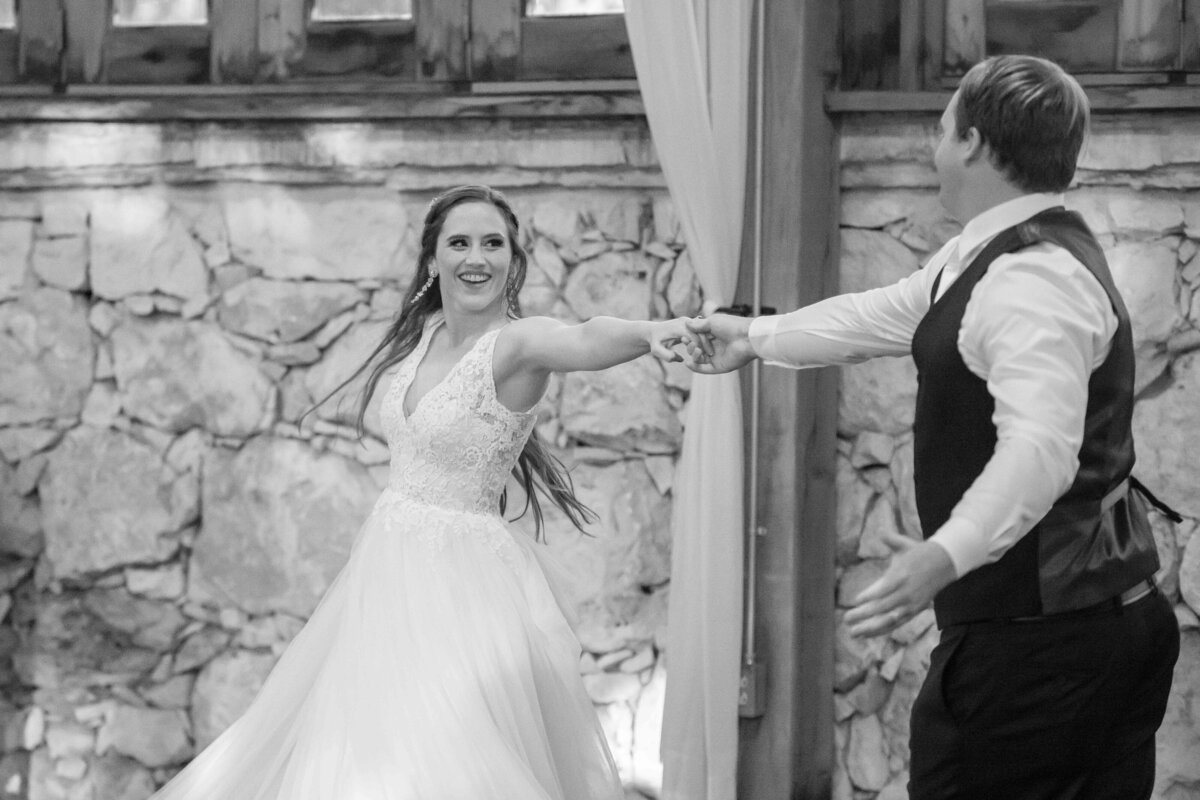 black and white image of bride and groom dancing as she spins Milltown Historic District wedding in New Braunfels Texas