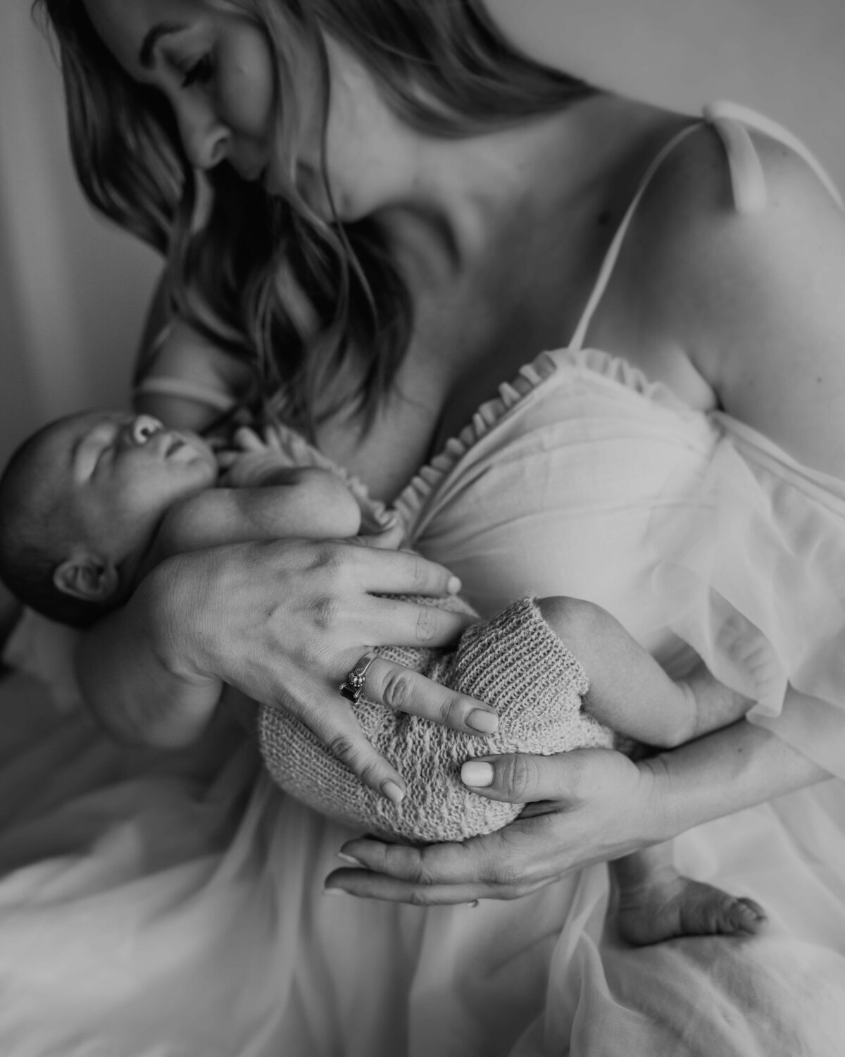 emotive mother wearing a chiffon dress holding her newborn