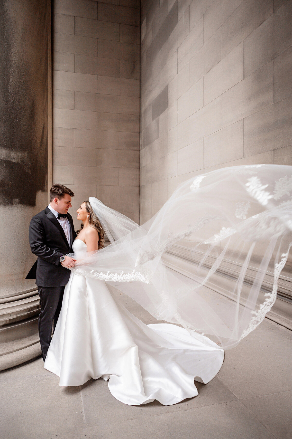 bride veil blowing in wind during winter wedding picture at mellon institute columns in pittsburgh