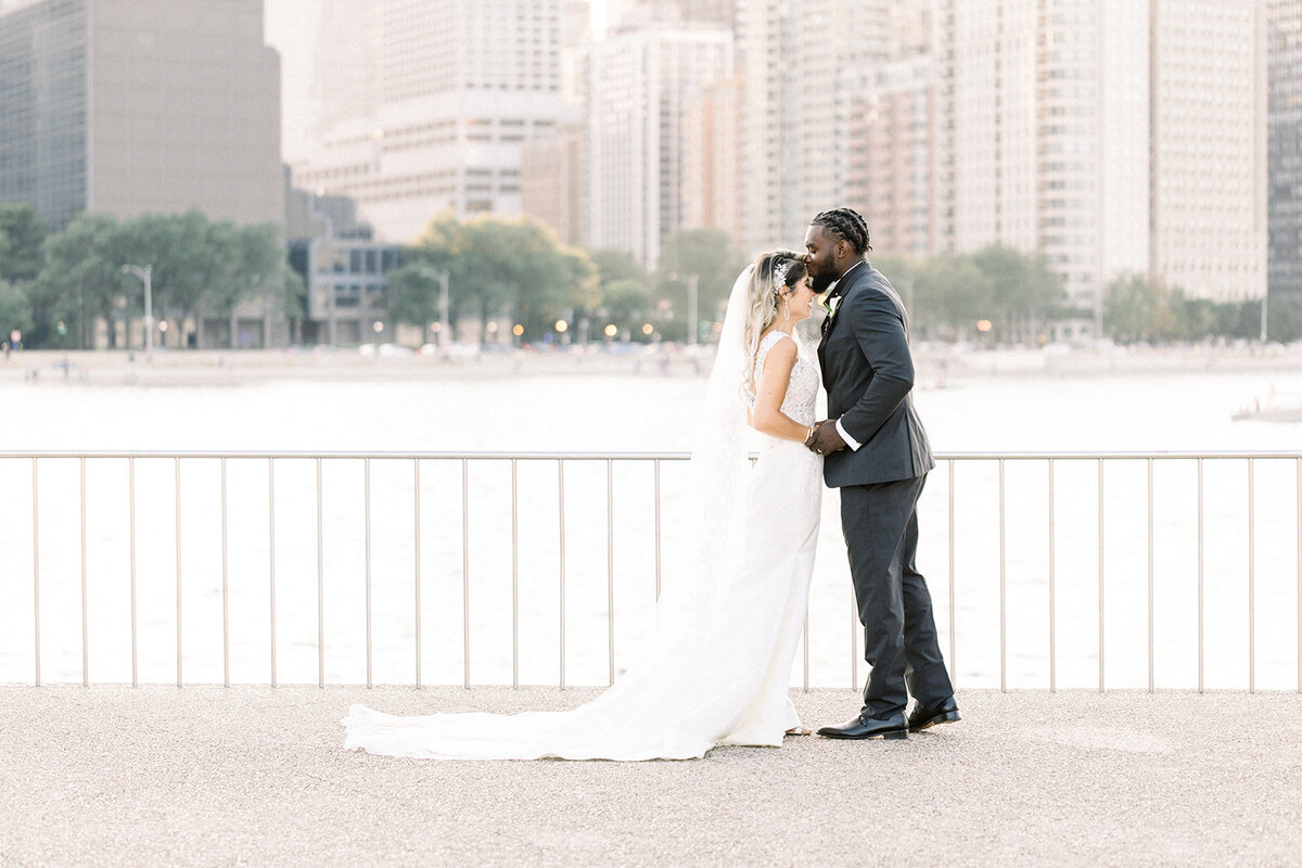 groom kissing bride's head in front of chicago skyline