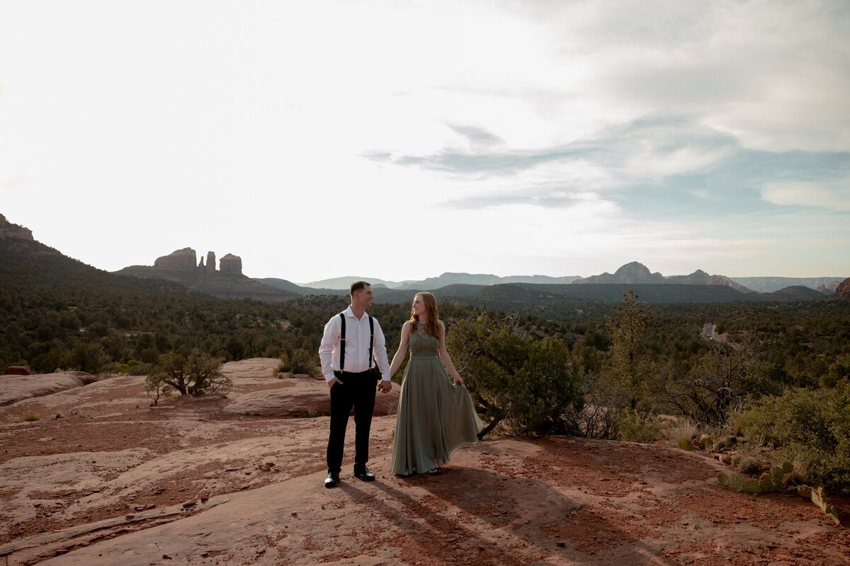 Couple standing against red rock backdrop during Sedona engagement session