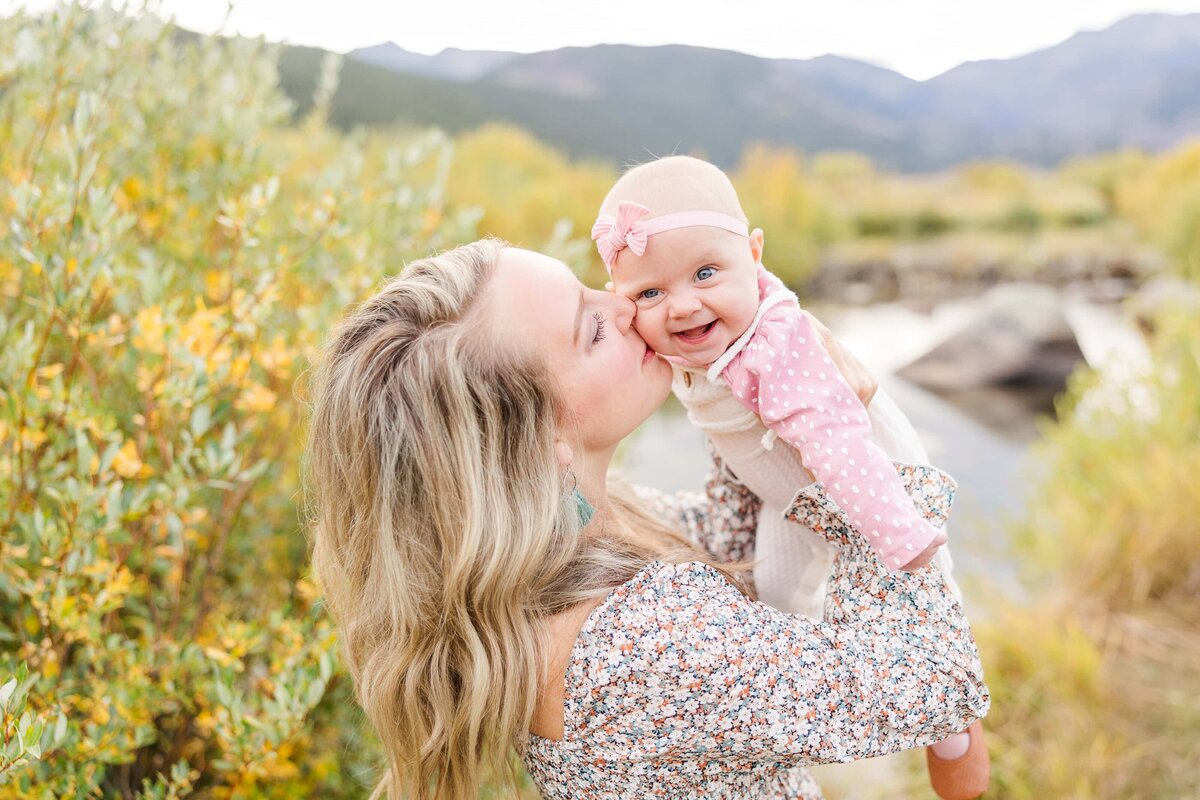 mom kisses cheek of her baby girl next to the Big Thompson River in Colorado